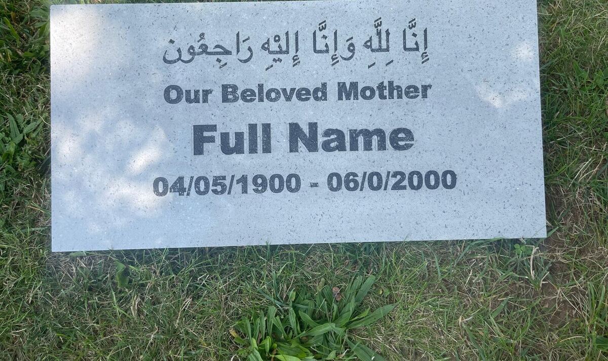 Close view of a white terrazzo marker with Qur'anic verse and dates