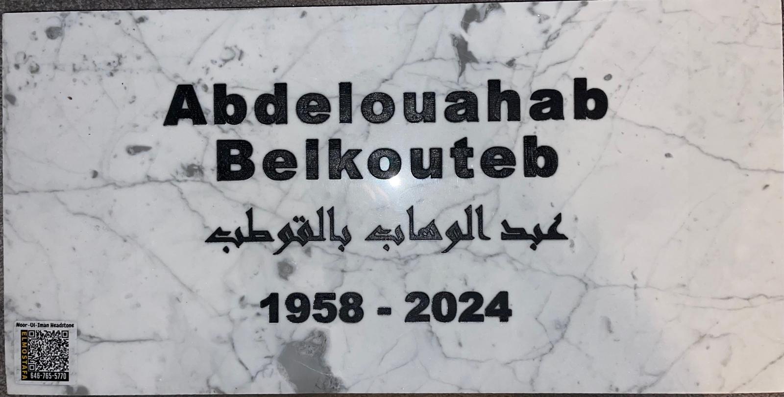 Close-up of an engraved marble headstone showing hand-carved Arabic and English lettering